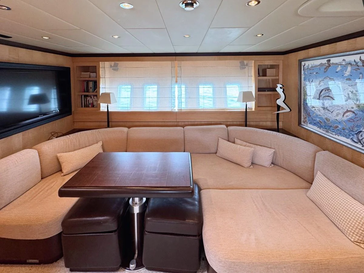 The salon features a comfortable seating area with a large sectional sofa and a central table, perfect for relaxation and socializing. aboard CARO Yacht for Sale