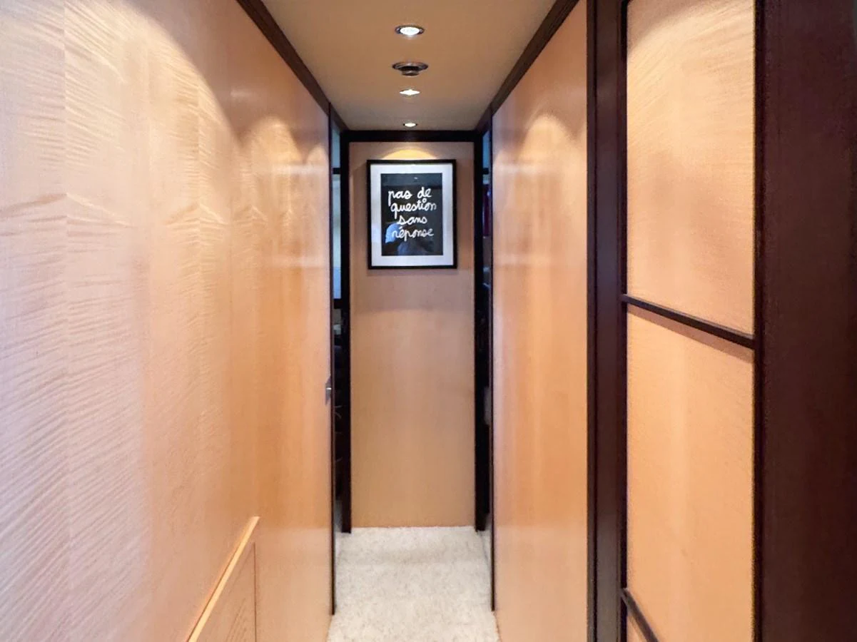 A sleek hallway with warm wood paneling and a framed artwork at the end. aboard CARO Yacht for Sale