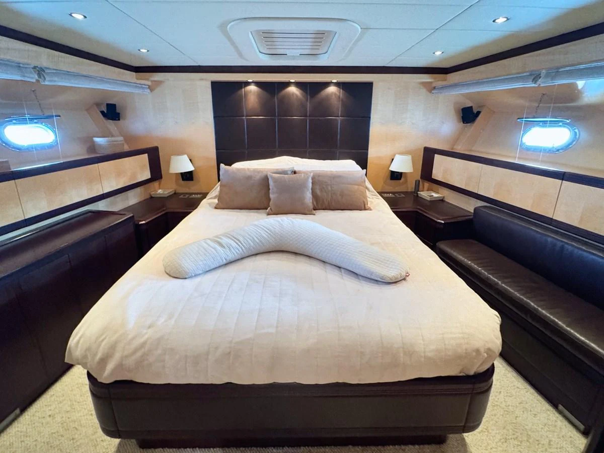 The master stateroom features a luxurious bed with elegant lighting and ample seating. aboard CARO Yacht for Sale