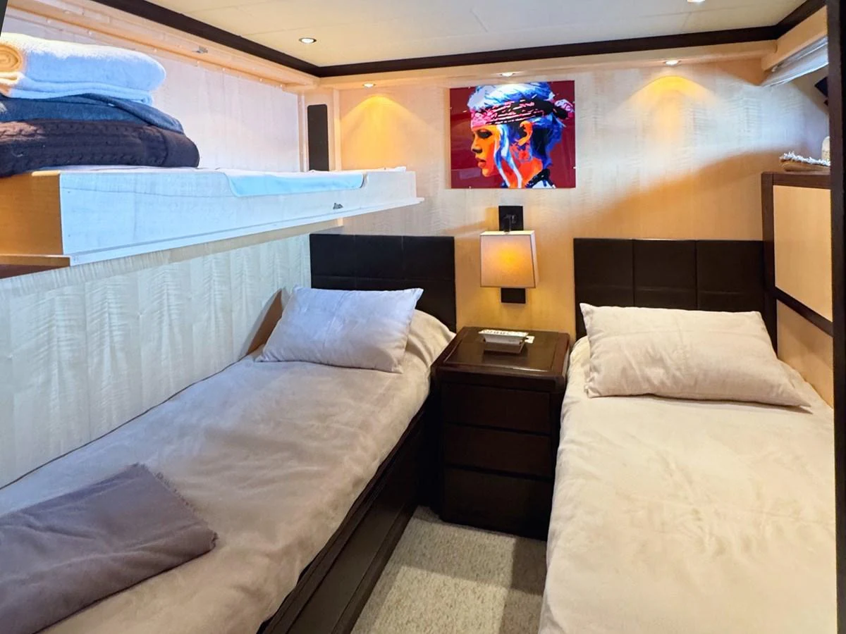 The twin stateroom features two single beds with modern decor and ambient lighting. aboard CARO Yacht for Sale