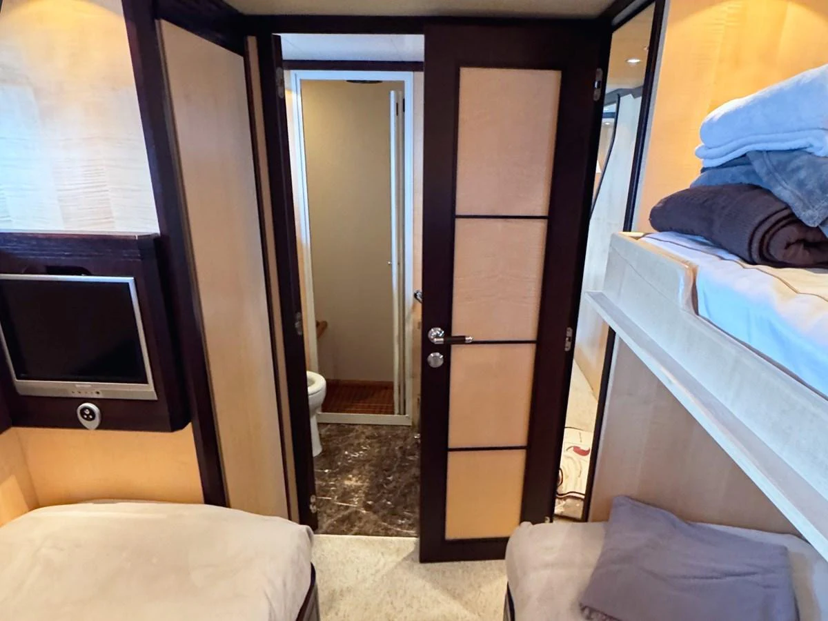A cozy cabin featuring twin beds, a television, and an en-suite bathroom. aboard CARO Yacht for Sale