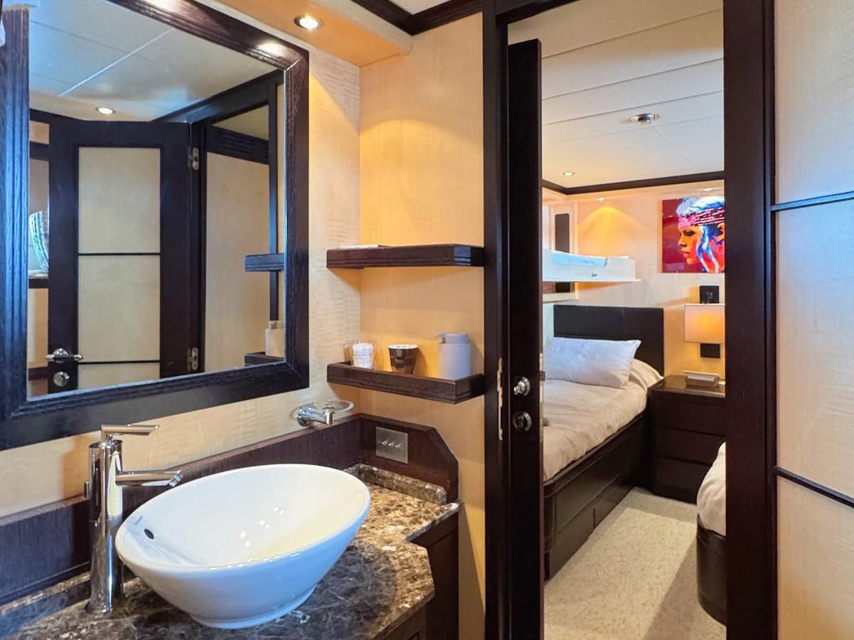 A cozy guest stateroom featuring a modern sink, a comfortable bed, and stylish decor. aboard CARO Yacht for Sale