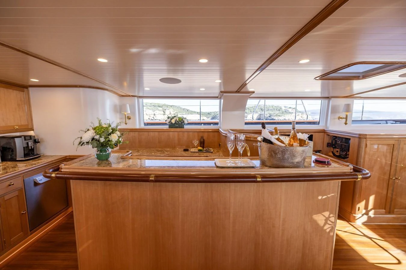 The galley features elegant wooden cabinetry and a well-appointed bar area with a view of the sea. aboard MAXIMUS Yacht for Sale