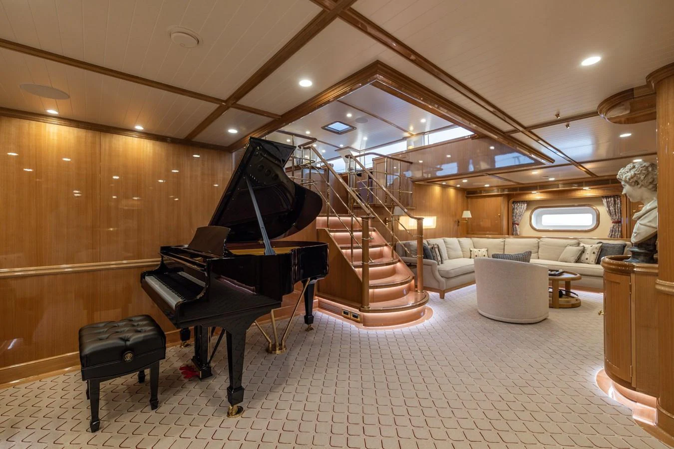 The salon features a grand piano, plush seating, and elegant wooden finishes, creating a luxurious and inviting atmosphere. aboard MAXIMUS Yacht for Sale