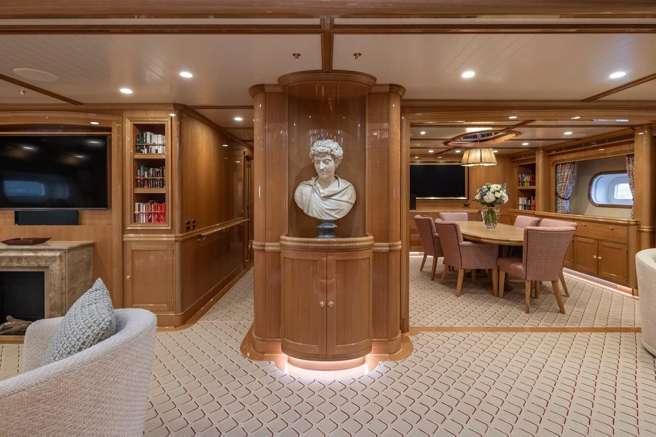 The salon features elegant wood paneling, a dining area, and a cozy seating arrangement. aboard MAXIMUS Yacht for Sale