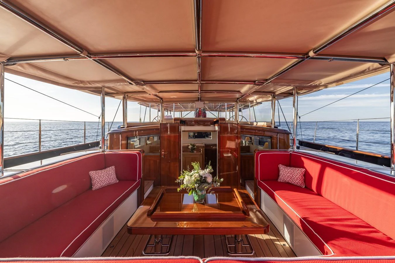 The aft deck features comfortable red seating and a wooden table, perfect for relaxation and socializing. aboard MAXIMUS Yacht for Sale