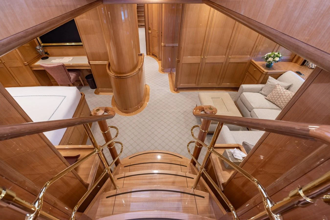 The yacht's interior features a luxurious staircase leading to a cozy living area with elegant wood finishes. aboard MAXIMUS Yacht for Sale