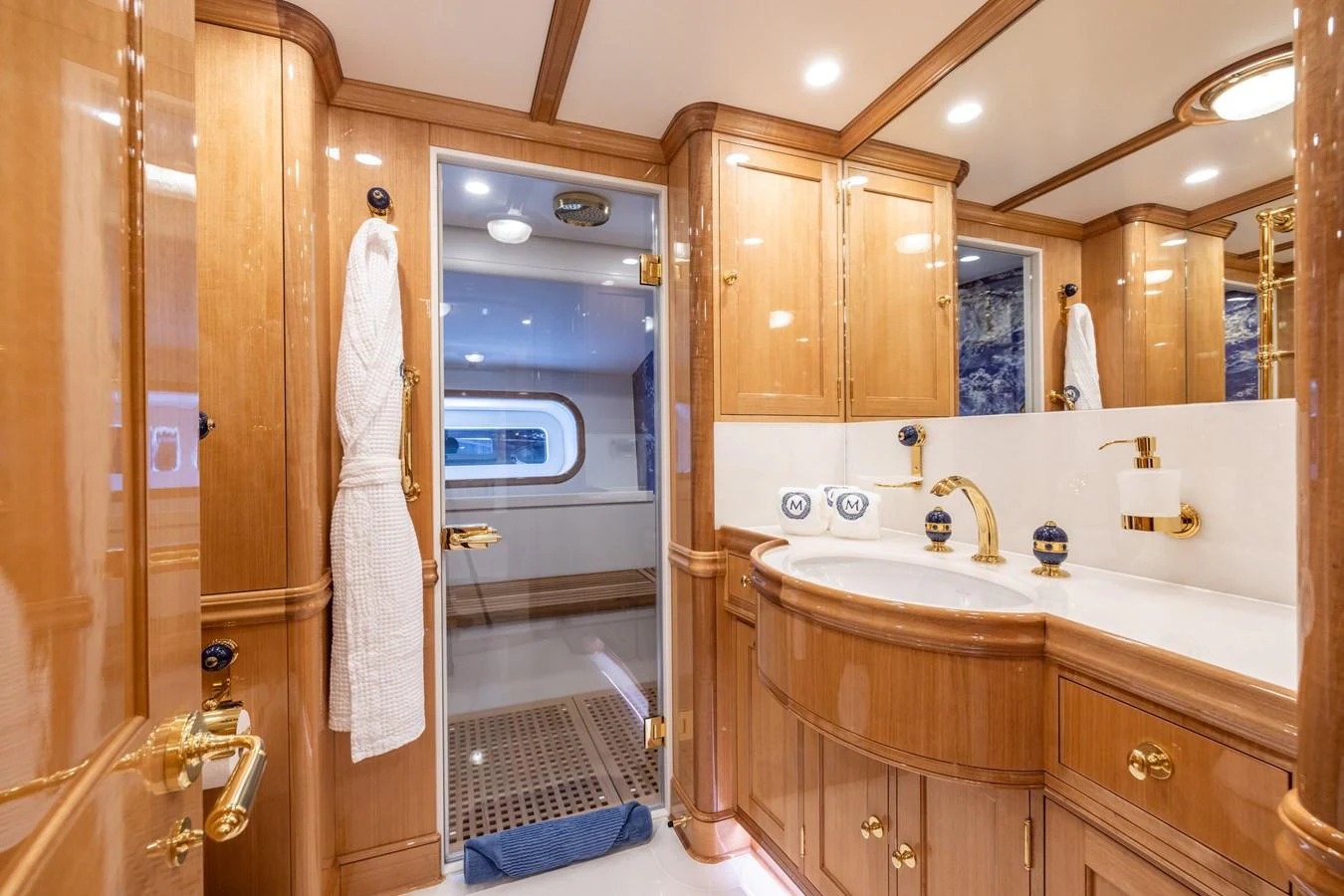 This luxurious yacht bathroom features elegant wooden cabinetry and gold fixtures. aboard MAXIMUS Yacht for Sale