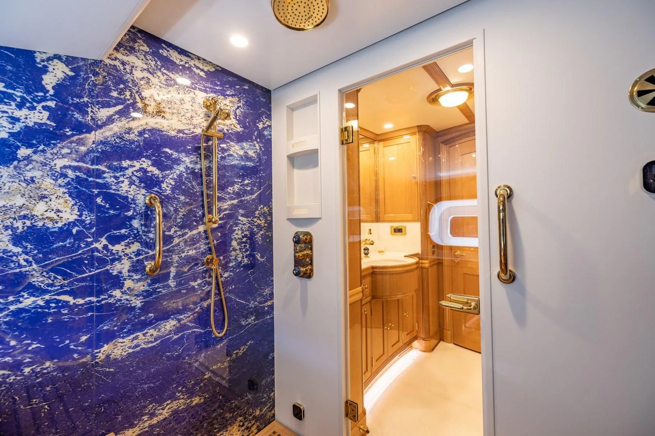 The yacht's bathroom features a luxurious shower with striking blue marble walls and gold fixtures. aboard MAXIMUS Yacht for Sale
