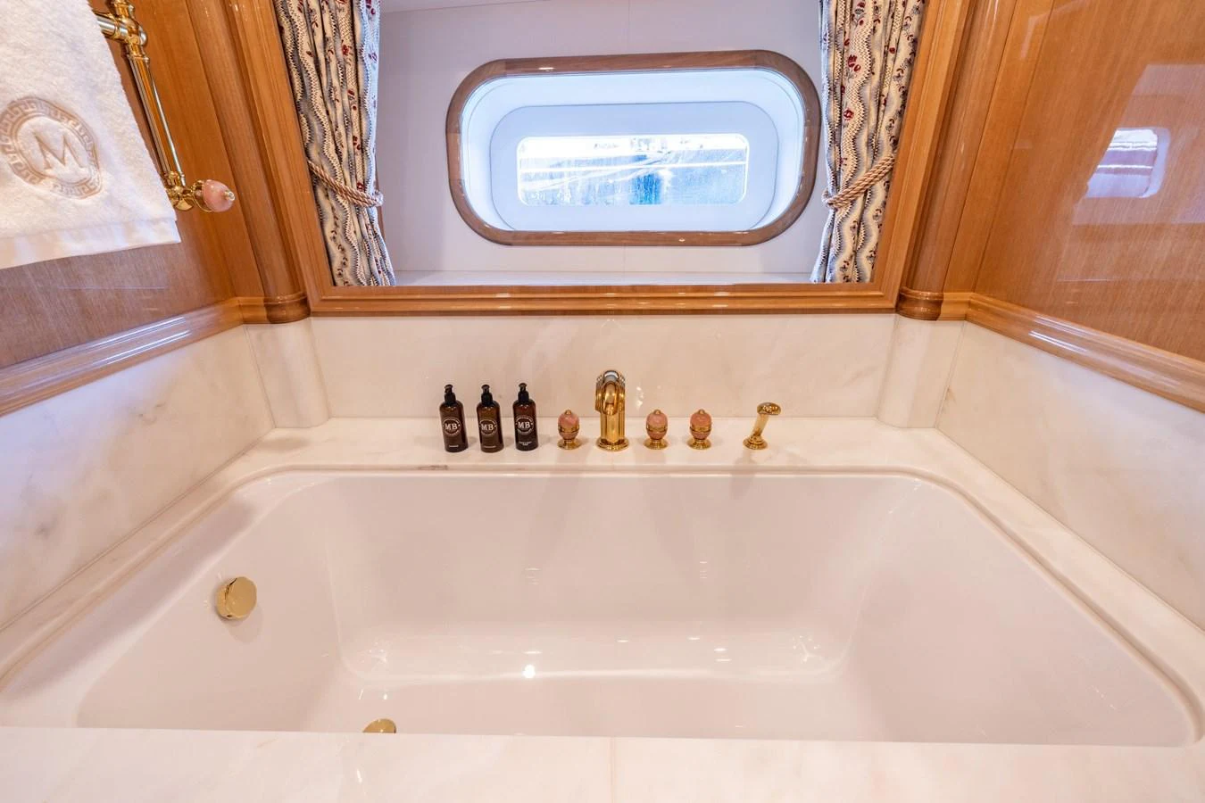 The yacht's bathroom features a luxurious bathtub with elegant fixtures and a view through a porthole window. aboard MAXIMUS Yacht for Sale