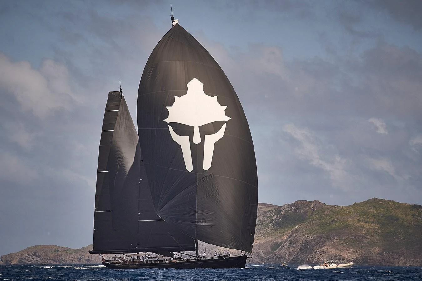 A sleek sailing yacht with striking black sails glides gracefully on the open water against a scenic backdrop. aboard MAXIMUS Yacht for Sale