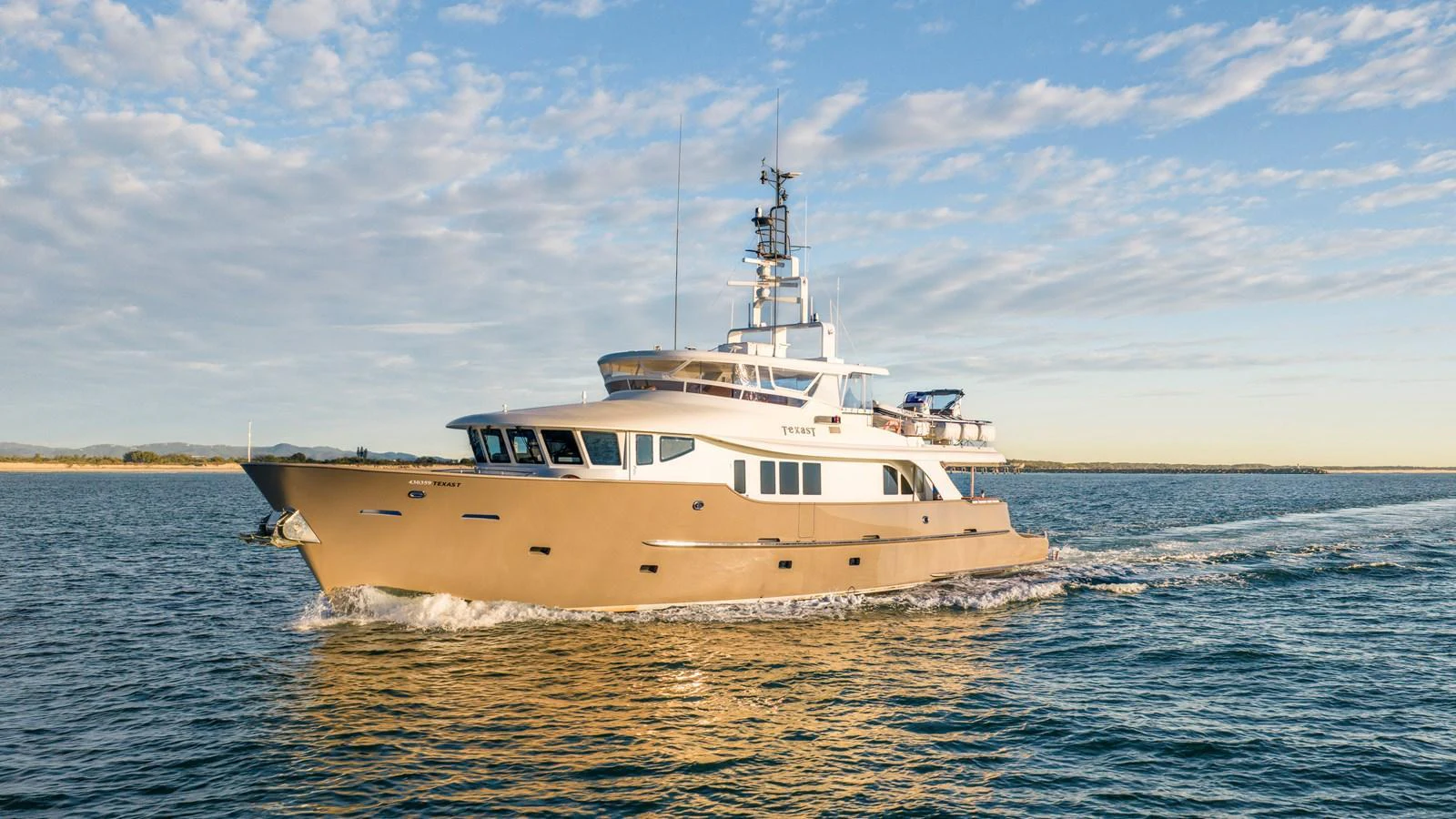 A luxurious yacht cruises through calm waters under a clear sky. aboard TEXAS T Yacht for Sale
