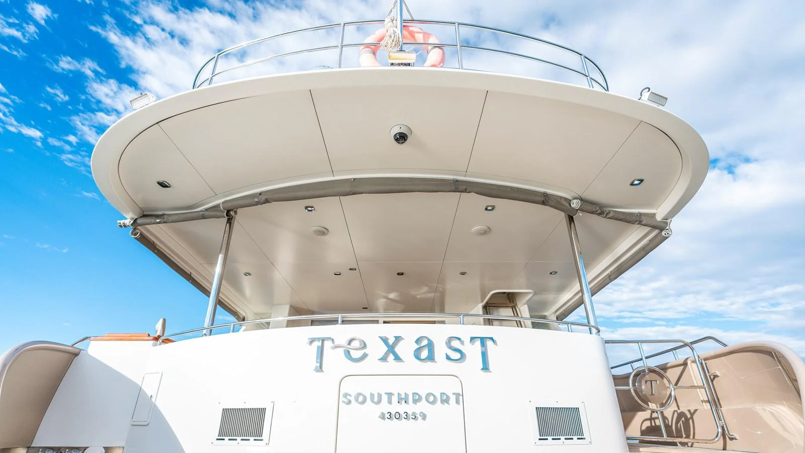 The yacht's aft deck showcases a spacious and inviting area under a clear blue sky. aboard TEXAS T Yacht for Sale
