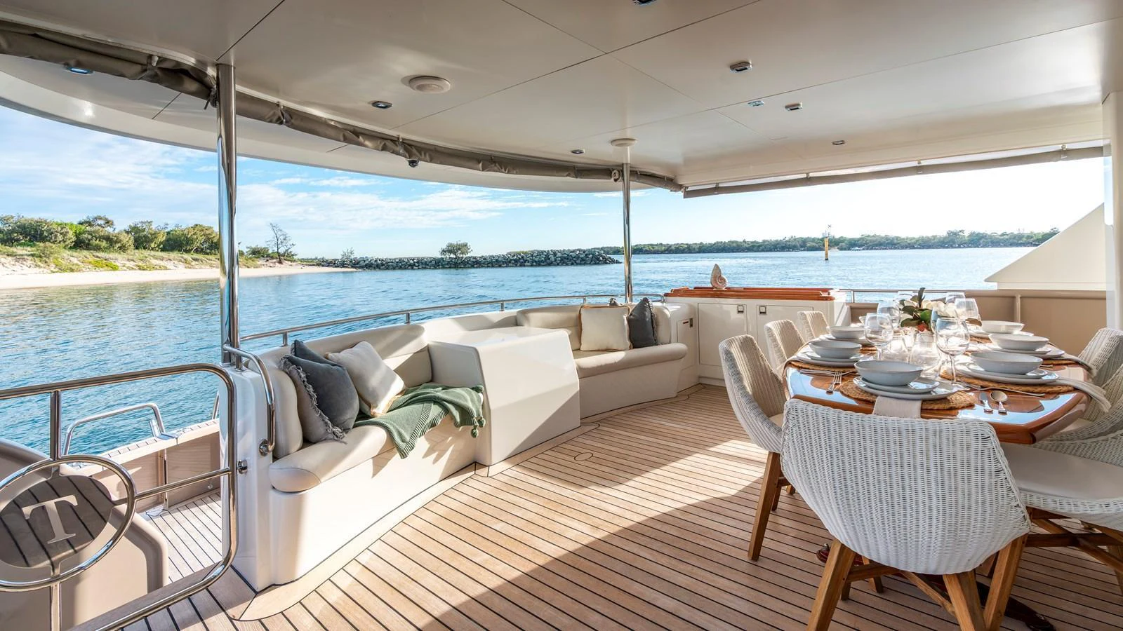 The aft deck features a spacious seating area and a beautifully set dining table with a stunning view of the water. aboard TEXAS T Yacht for Sale