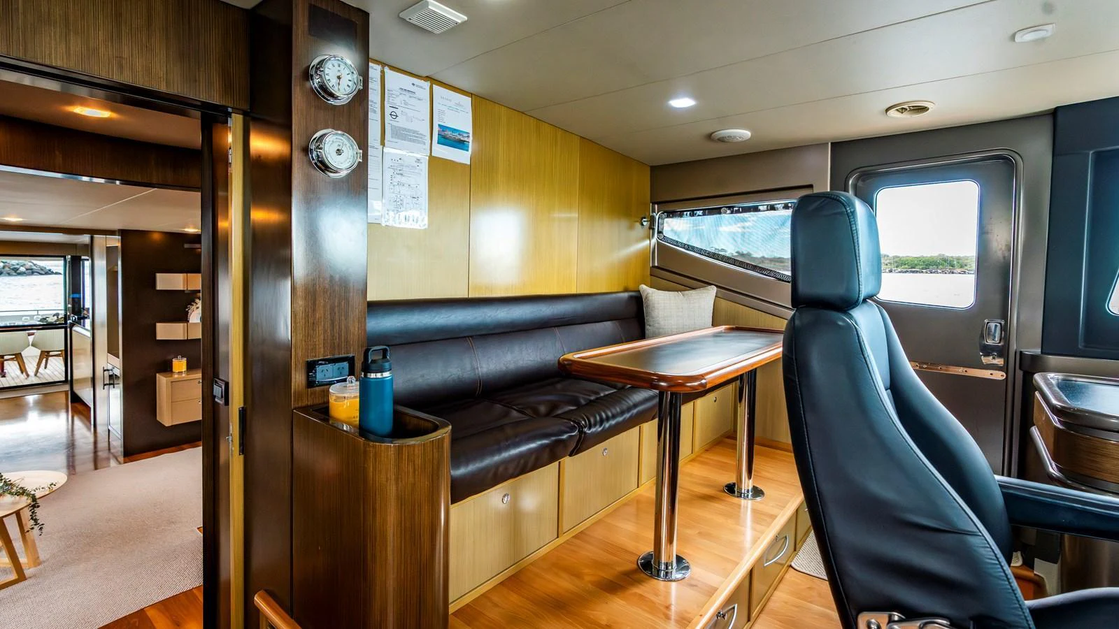 The helm area features a comfortable seating arrangement with a wooden table and a sleek captain's chair. aboard TEXAS T Yacht for Sale
