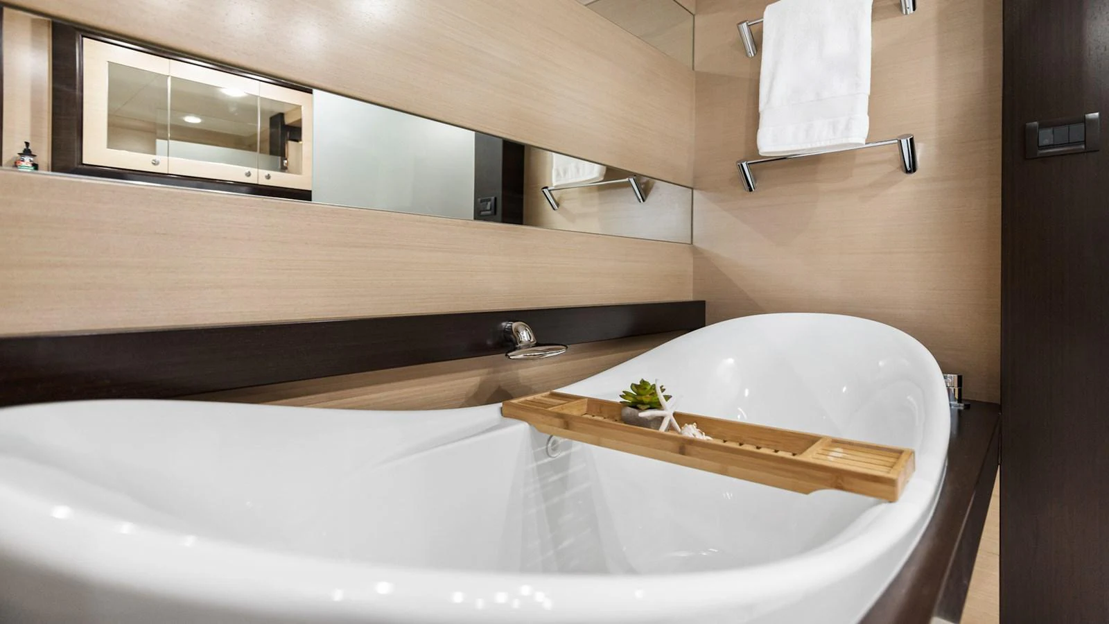 The yacht's bathroom features a sleek, modern bathtub with elegant fixtures and a wooden tray for added convenience. aboard TEXAS T Yacht for Sale