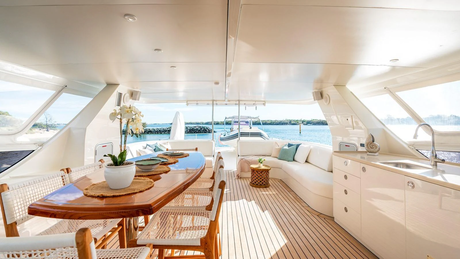The aft deck features an elegant dining area with a polished wooden table and comfortable seating, perfect for alfresco meals. aboard TEXAS T Yacht for Sale