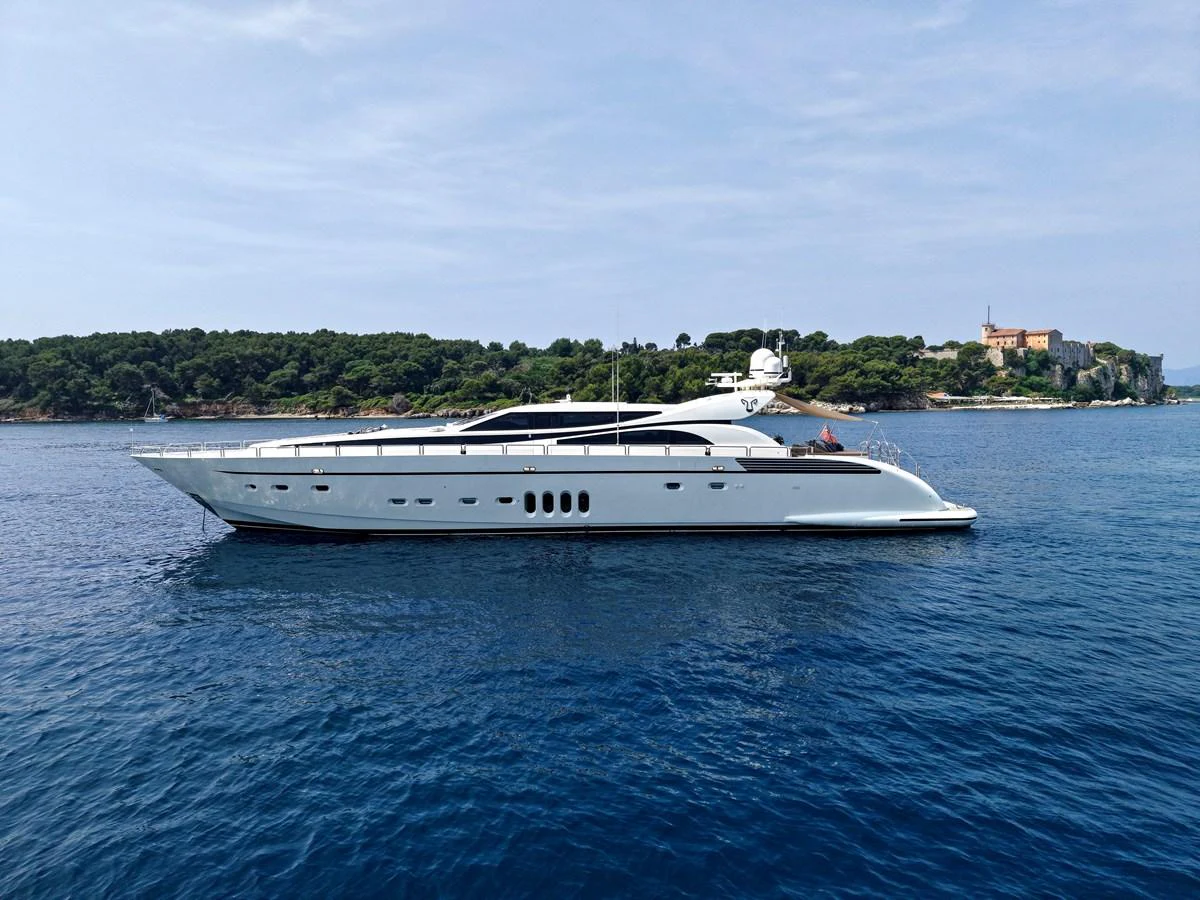 A sleek and modern yacht glides gracefully on calm blue waters with a scenic coastline in the background. aboard CHEEKY TIGER Yacht for Sale