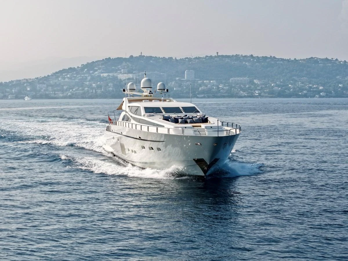 A sleek yacht cruises through calm waters with a scenic coastal backdrop. aboard CHEEKY TIGER Yacht for Sale