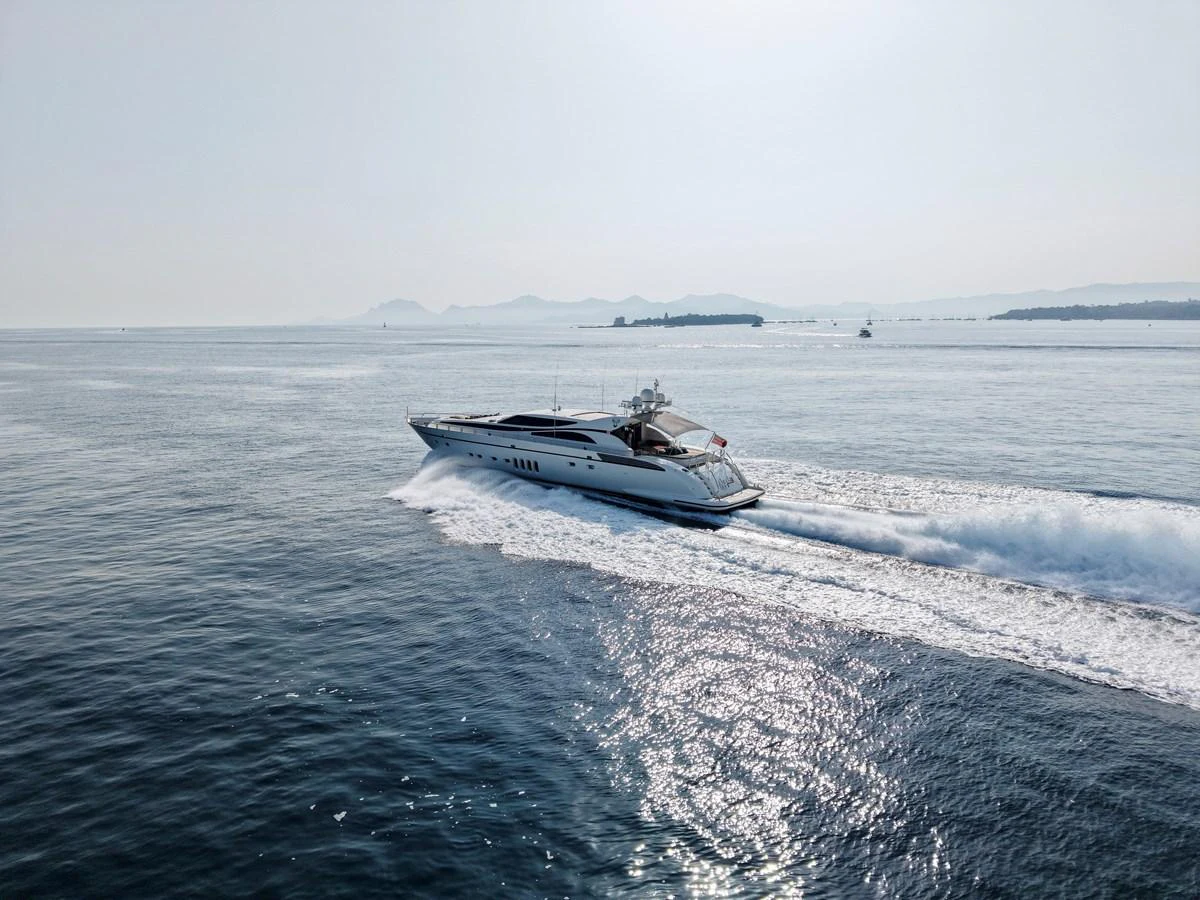 A sleek yacht cruises swiftly across calm waters with a scenic backdrop. aboard CHEEKY TIGER Yacht for Sale