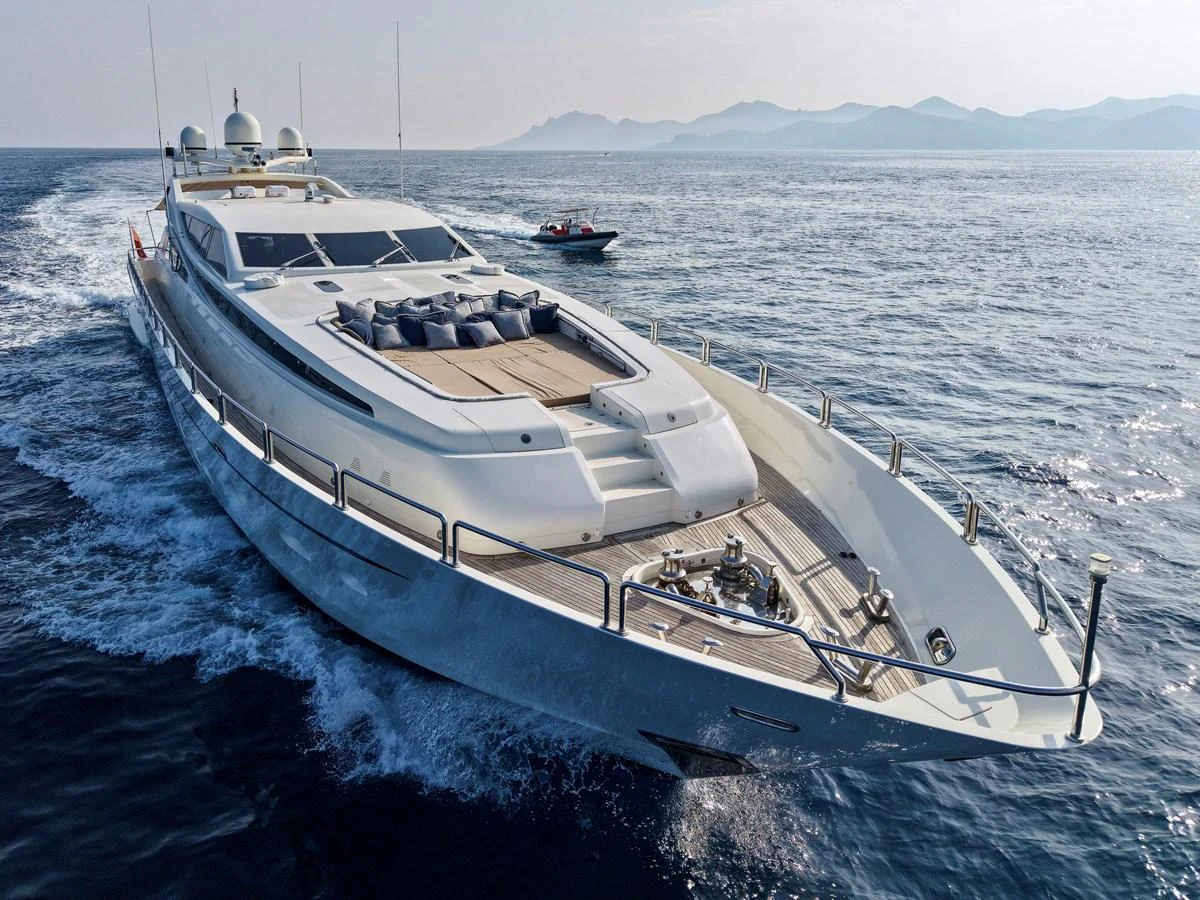A sleek and modern yacht cruising through open waters with a stunning backdrop of distant mountains. aboard CHEEKY TIGER Yacht for Sale