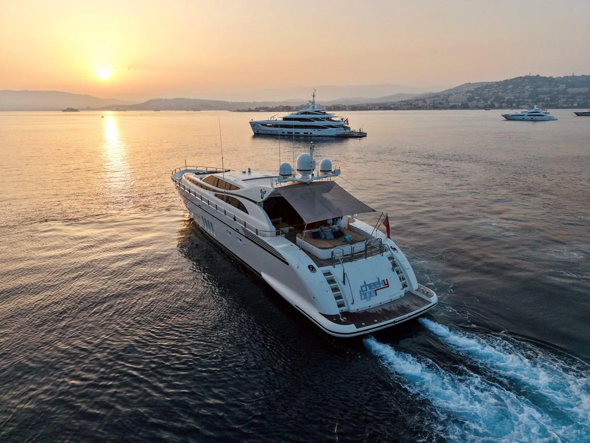 A sleek yacht cruises through calm waters at sunset, showcasing its elegant design and spacious deck. aboard CHEEKY TIGER Yacht for Sale