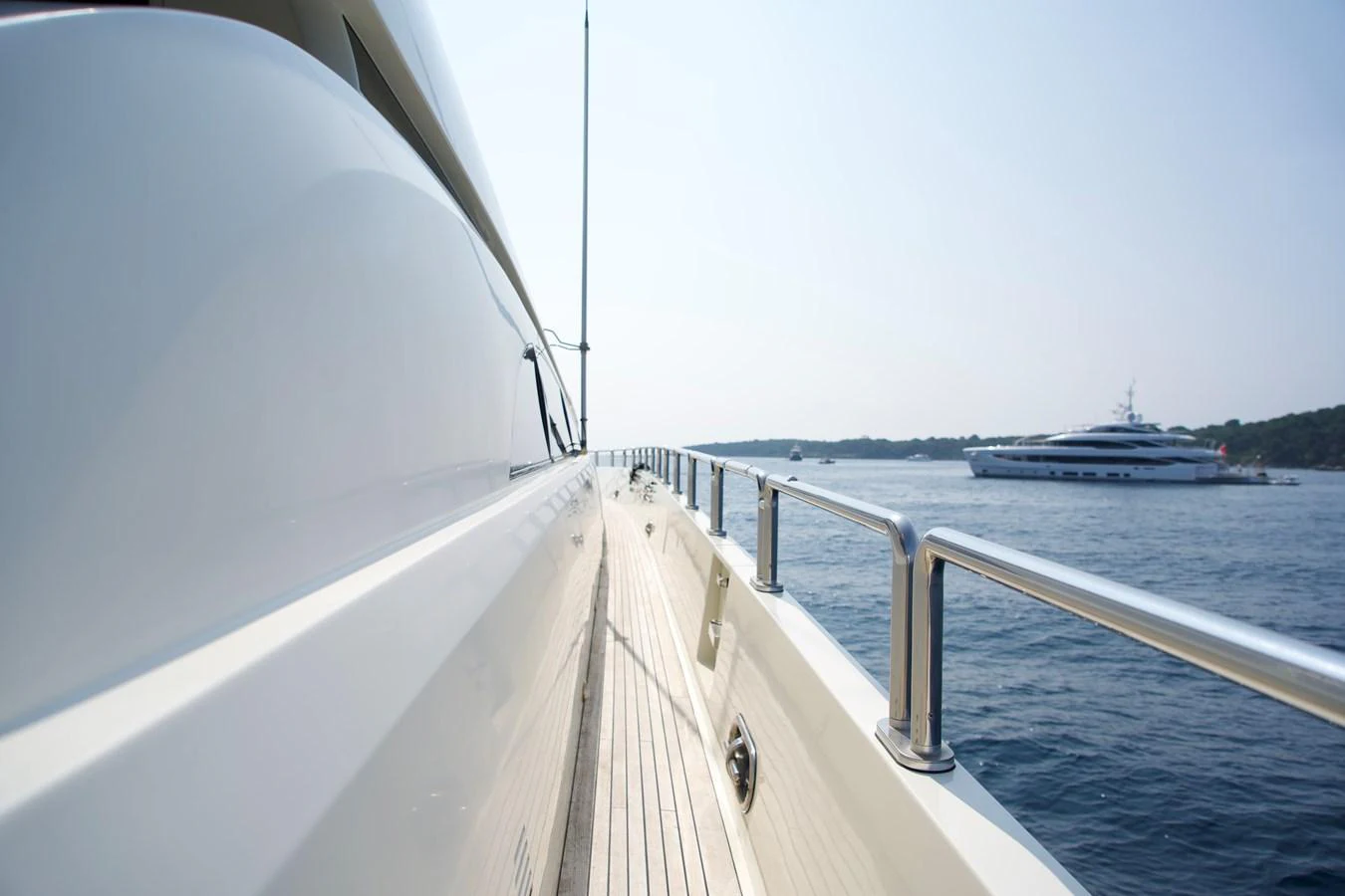 The sleek side deck of a luxury yacht offers a stunning view of the open sea and another yacht in the distance. aboard CHEEKY TIGER Yacht for Sale