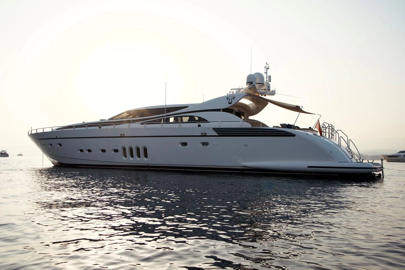 A sleek and modern yacht glides gracefully on calm waters at sunset. aboard CHEEKY TIGER Yacht for Sale