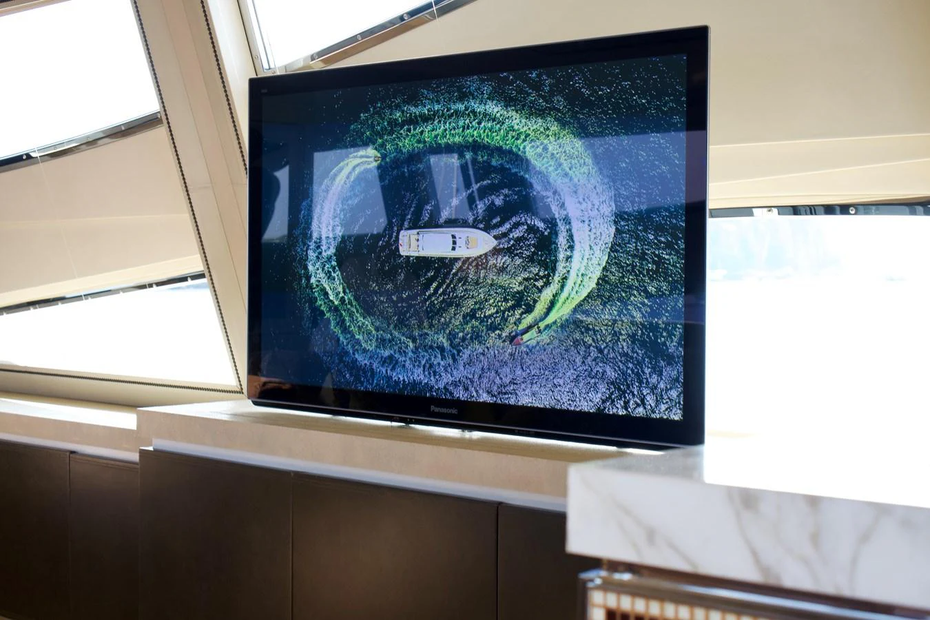 A luxurious interior space featuring a flat-screen television displaying an aerial view of a yacht. aboard CHEEKY TIGER Yacht for Sale