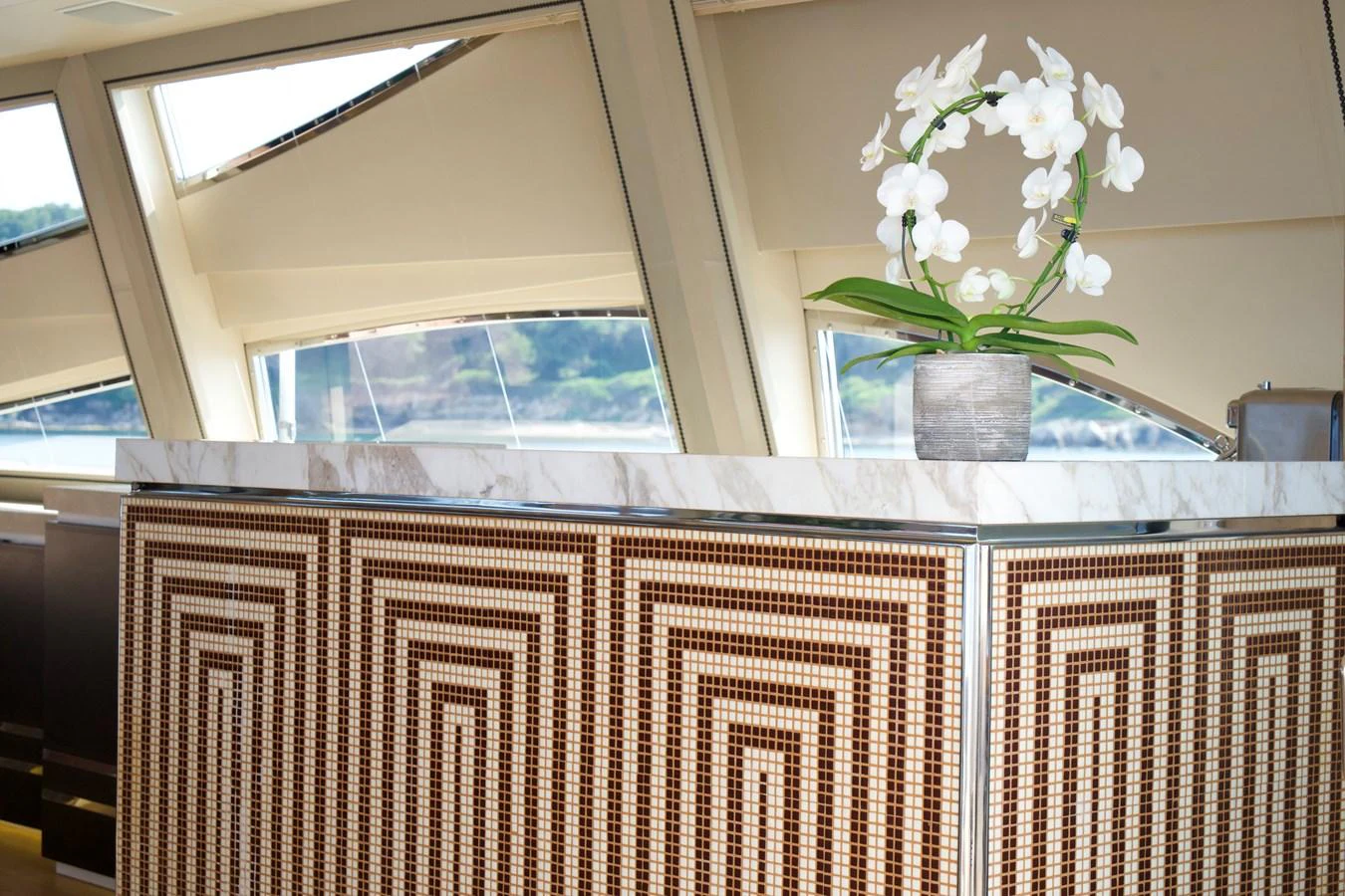 The yacht's interior features a stylish bar area with intricate woodwork and a touch of elegance from a white orchid arrangement. aboard CHEEKY TIGER Yacht for Sale