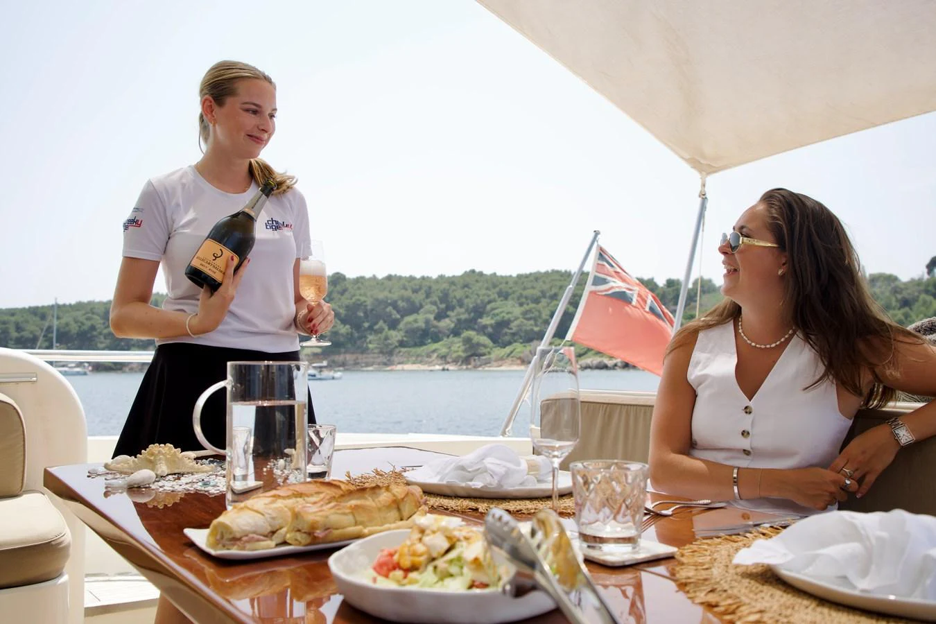 Guests enjoy a luxurious meal on the yacht's deck with a scenic view in the background. aboard CHEEKY TIGER Yacht for Sale