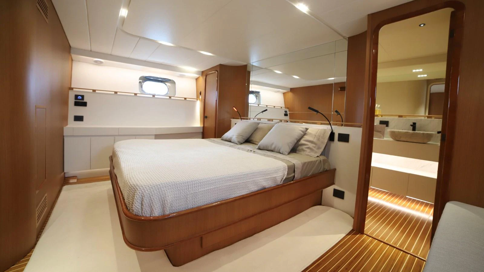 The master stateroom features a spacious bed with elegant wood finishes and ample natural light. aboard MAVERICK Yacht for Sale
