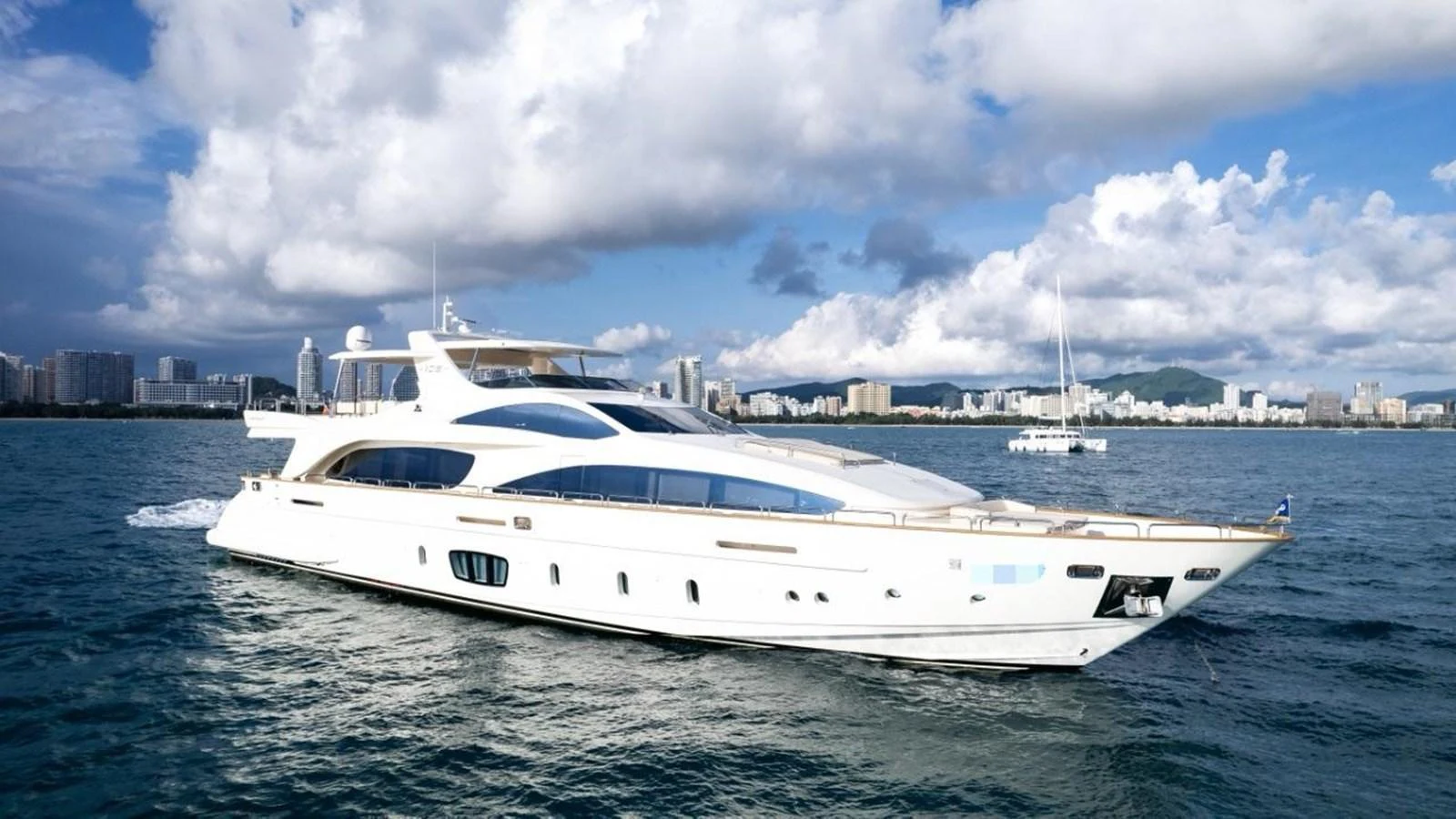 A sleek and modern yacht cruising on calm waters with a cityscape in the background. aboard AZIMUT 105 Yacht for Sale