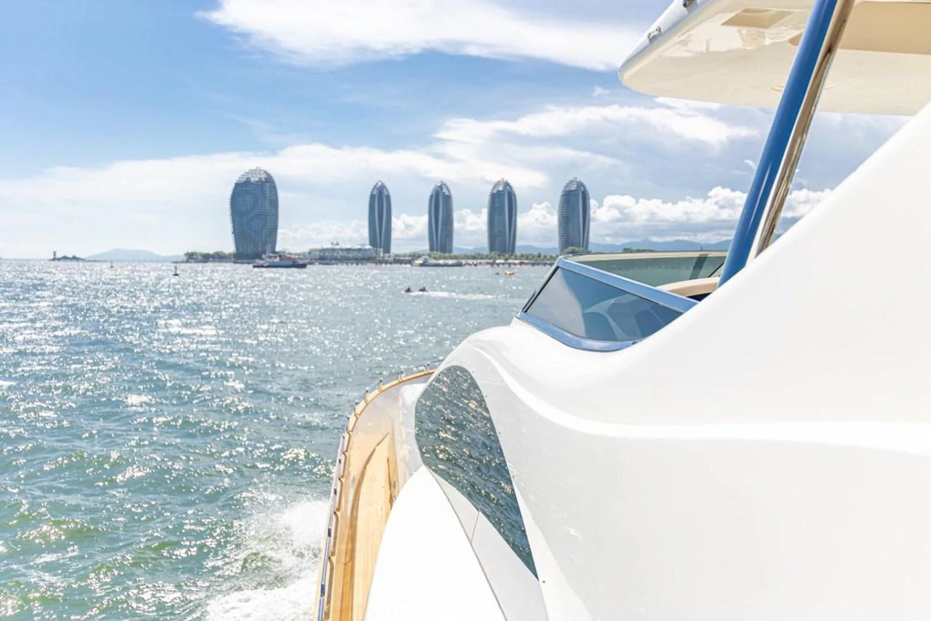 The yacht glides through sparkling waters with a modern cityscape in the background. aboard AZIMUT 105 Yacht for Sale