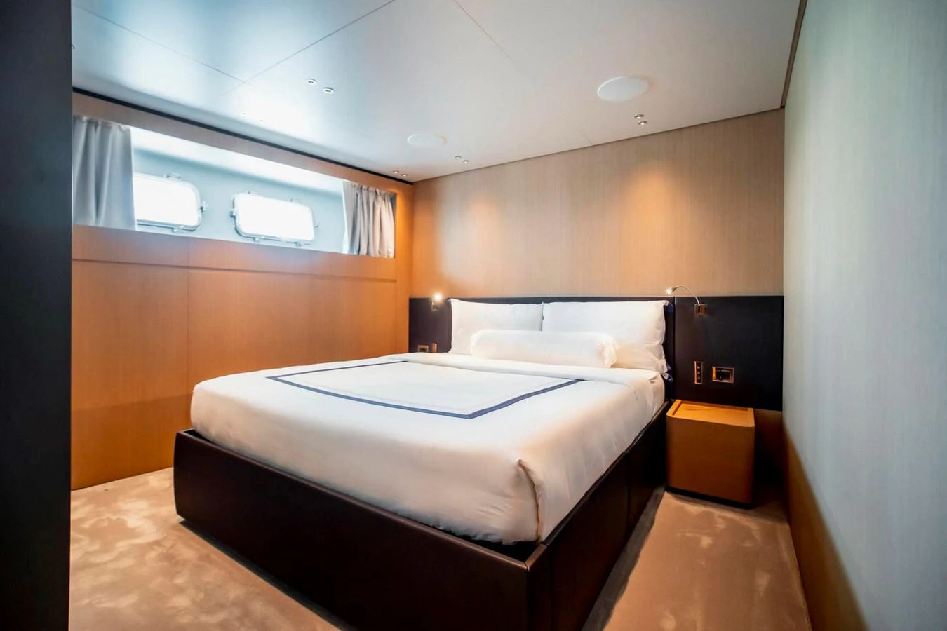The stateroom features a plush bed with modern, minimalist decor and ample natural light from the windows. aboard SANLORENZO SX100 Yacht for Sale