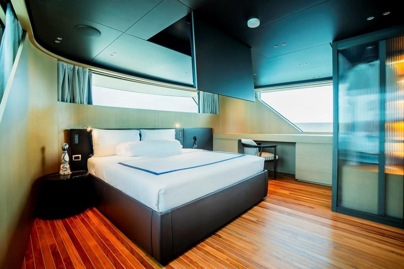 A luxurious stateroom featuring a large bed, wooden flooring, and ample natural light. aboard SANLORENZO SX100 Yacht for Sale