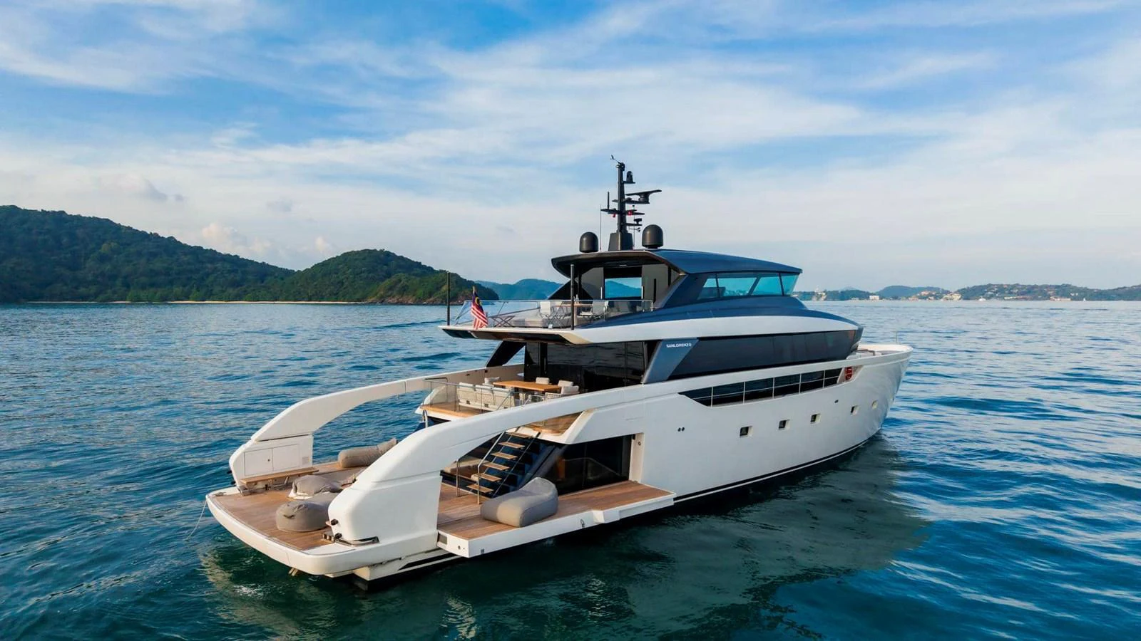 A sleek and modern yacht cruising on calm waters with scenic hills in the background. aboard SANLORENZO SX100 Yacht for Sale