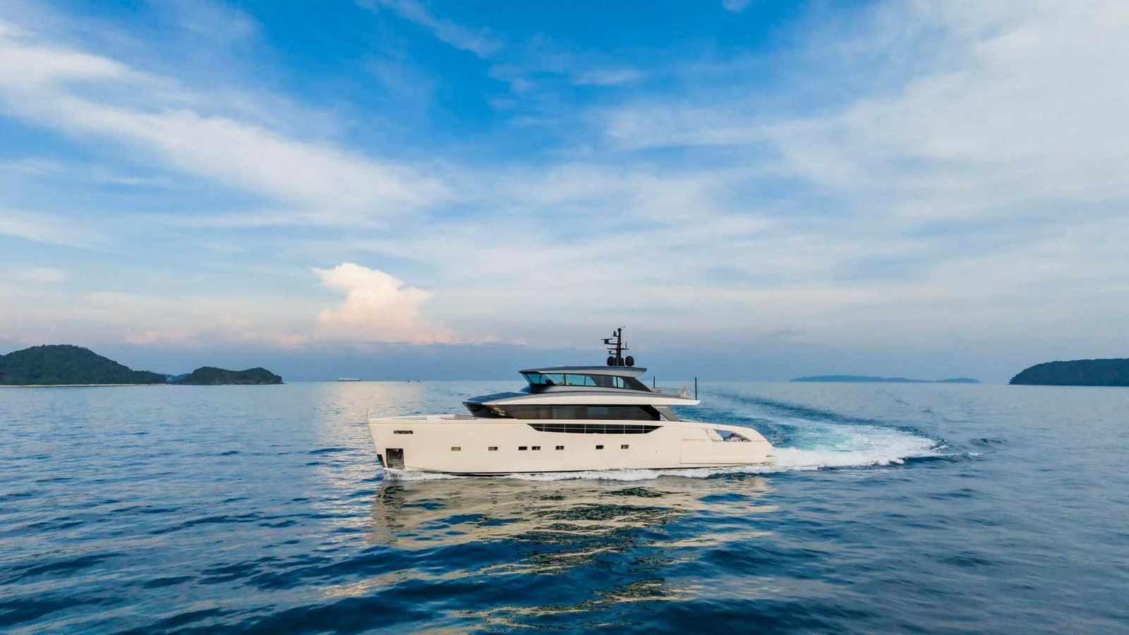 A sleek, modern yacht cruises through calm waters under a picturesque sky. aboard SANLORENZO SX100 Yacht for Sale