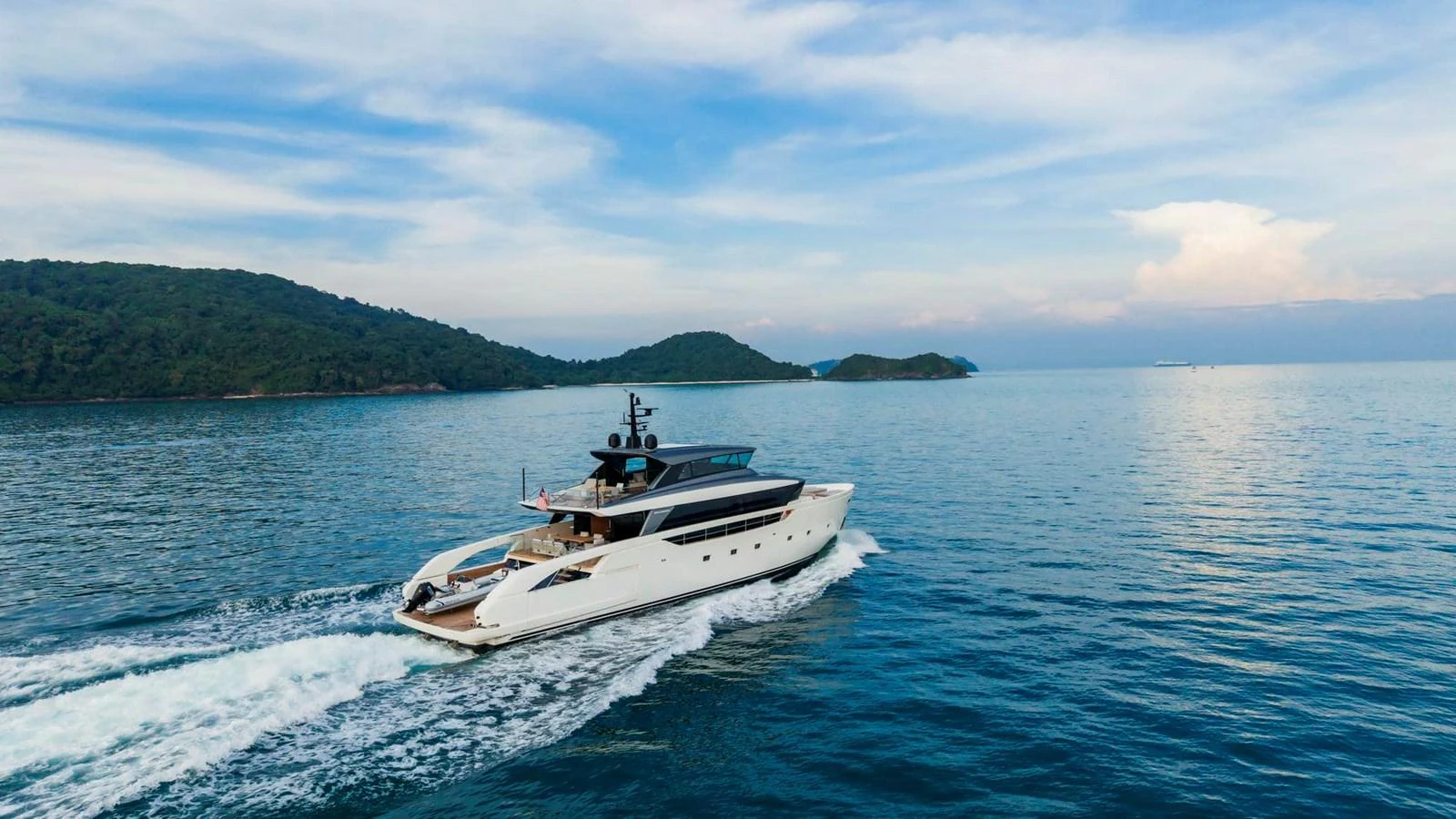 A sleek yacht cruises through calm waters with scenic islands in the background. aboard SANLORENZO SX100 Yacht for Sale