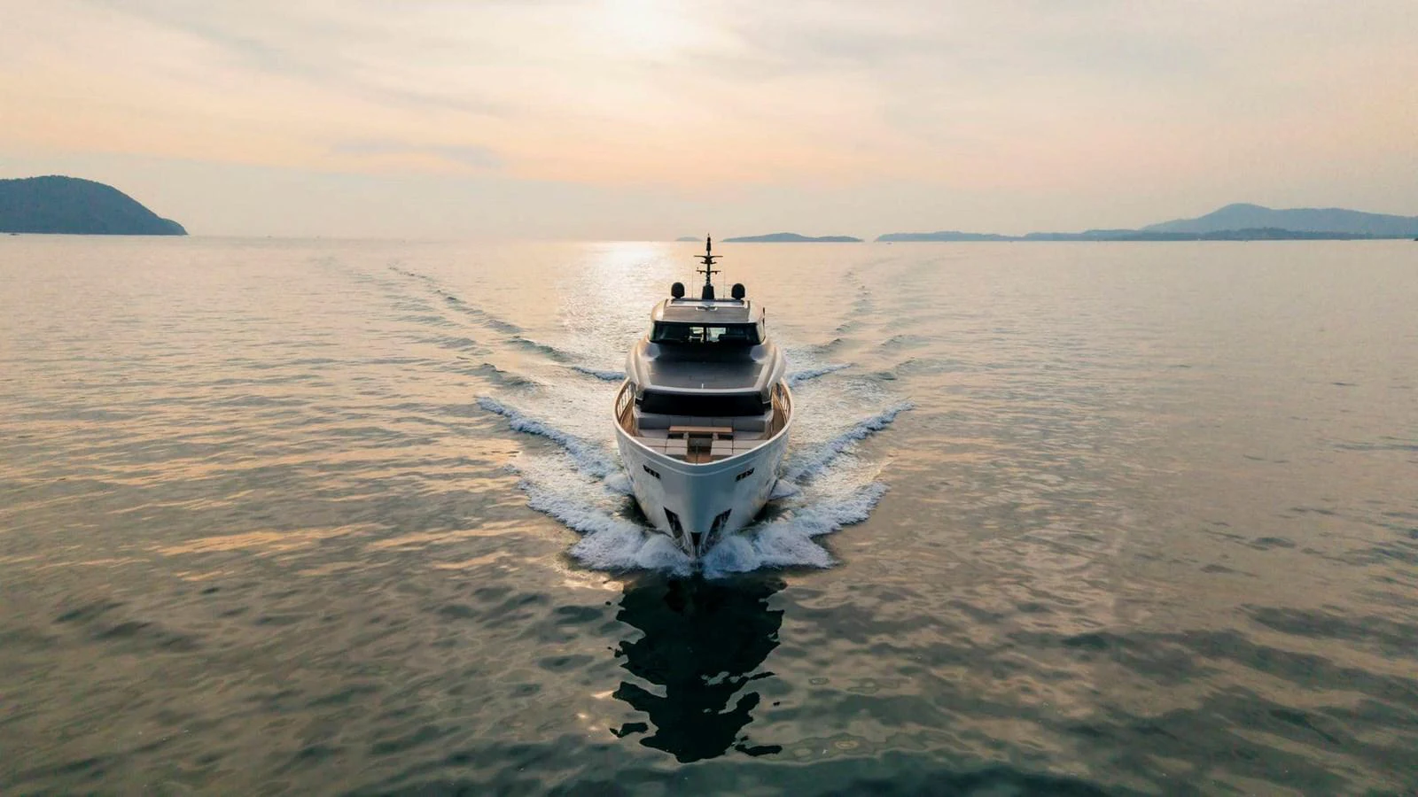 A sleek yacht cruises forward on calm waters during a serene sunset. aboard SANLORENZO SX100 Yacht for Sale