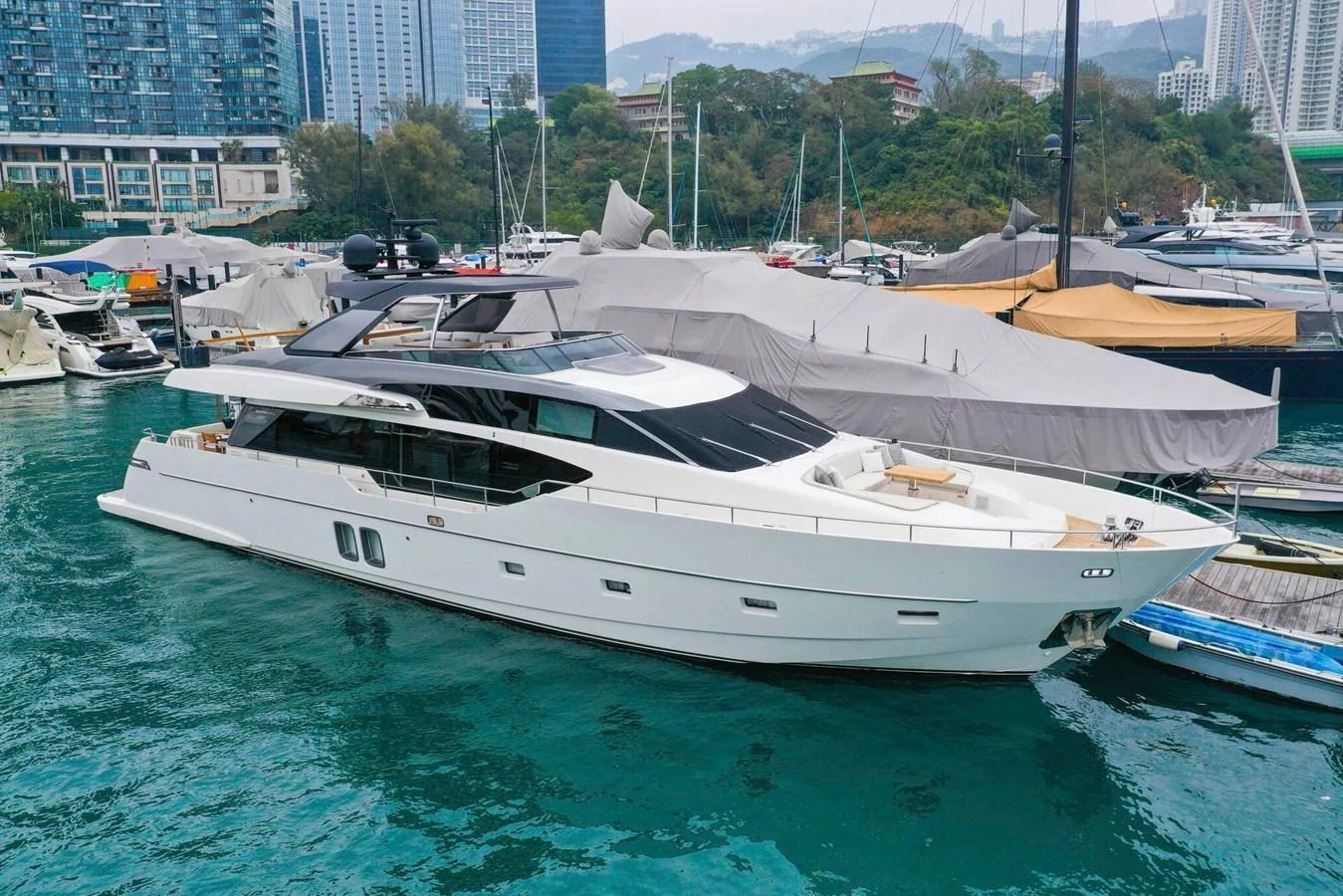 A sleek and modern yacht docked in a marina with a cityscape in the background. aboard SANLORENZO SL86 Yacht for Sale