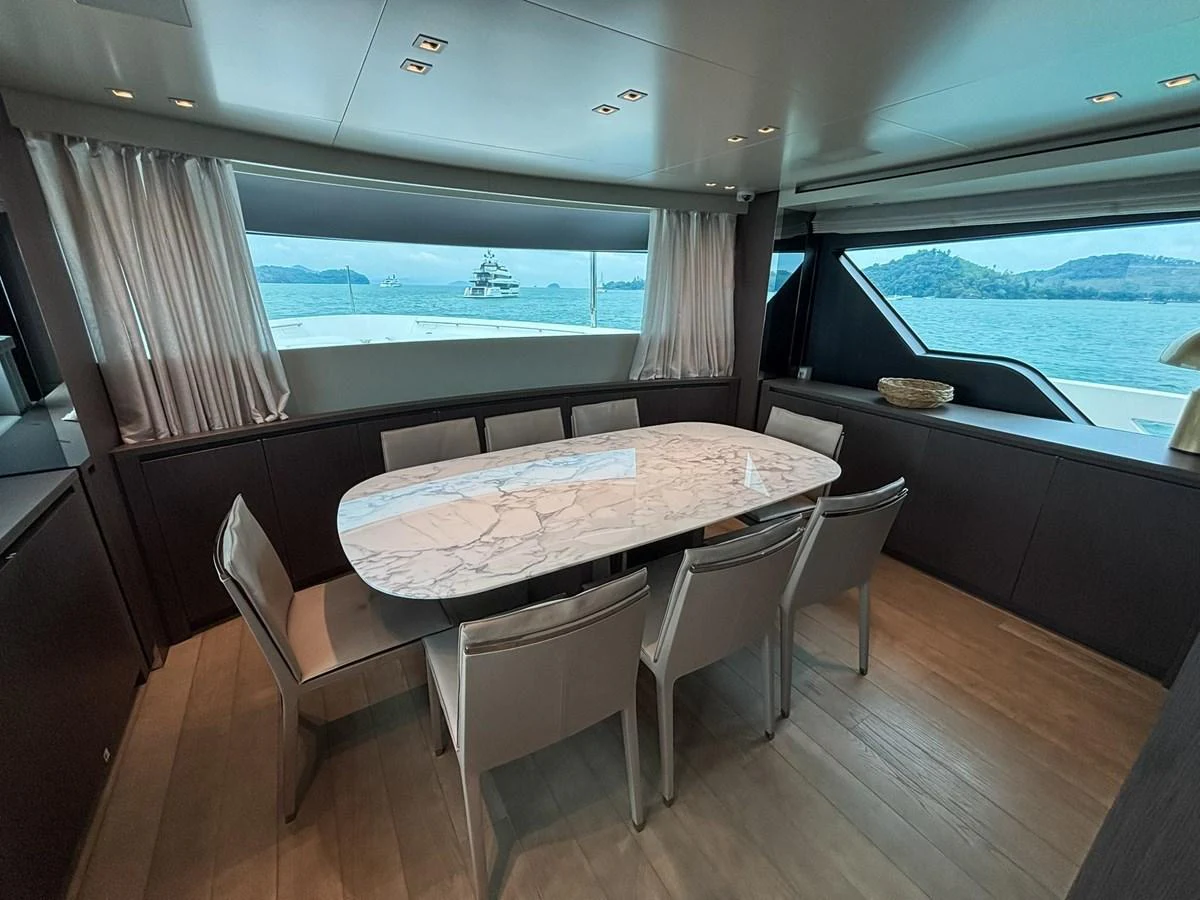 The yacht's dining area features a sleek marble table surrounded by modern chairs, with large windows offering stunning sea views. aboard SANLORENZO SX88 Yacht for Sale