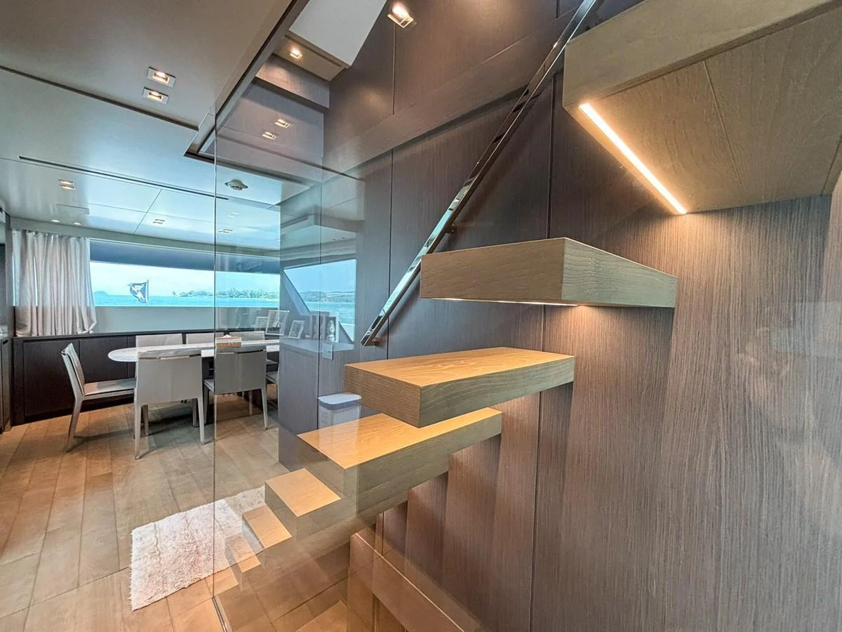 The image showcases a modern yacht salon with a stylish staircase and dining area. aboard SANLORENZO SX88 Yacht for Sale
