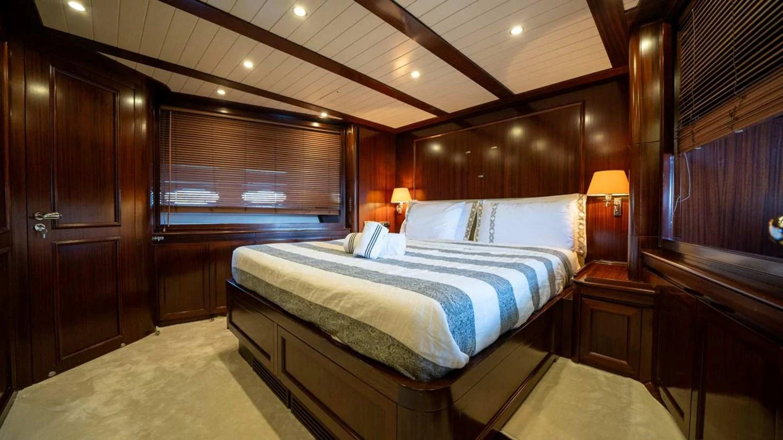 The master stateroom features a luxurious bed with elegant wood paneling and ambient lighting. aboard SILVER Yacht for Sale