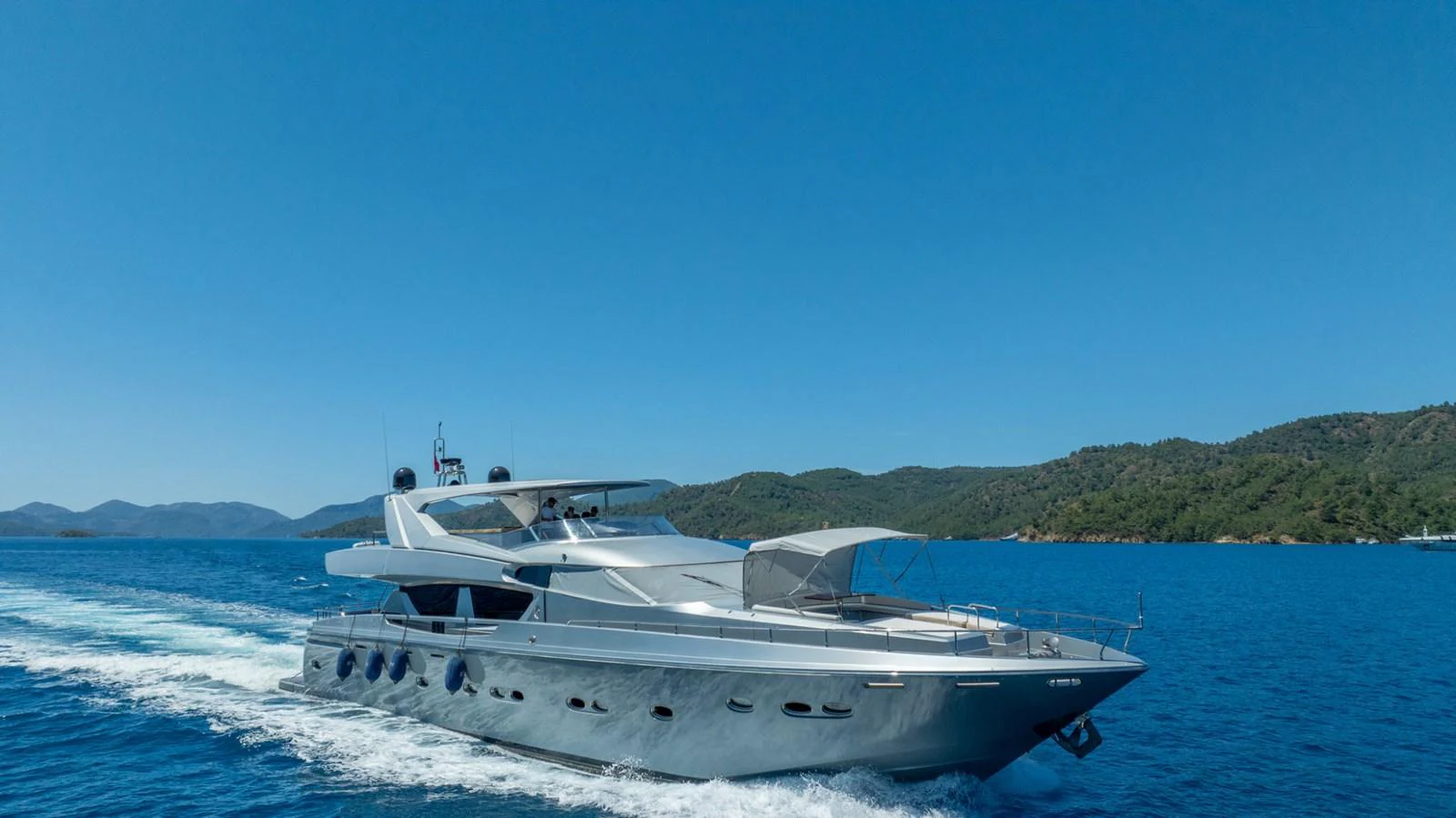 A sleek yacht cruises through clear blue waters under a bright sky. aboard SILVER Yacht for Sale