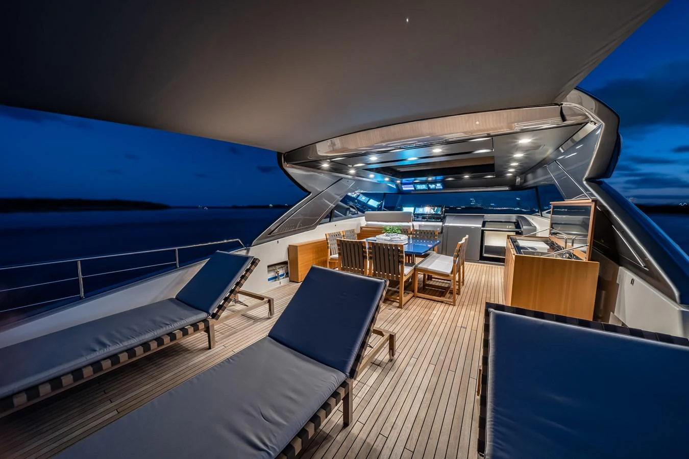 The flybridge offers a luxurious outdoor space with lounge chairs and a dining area under a sleek canopy. aboard VIOLETTA Yacht for Sale