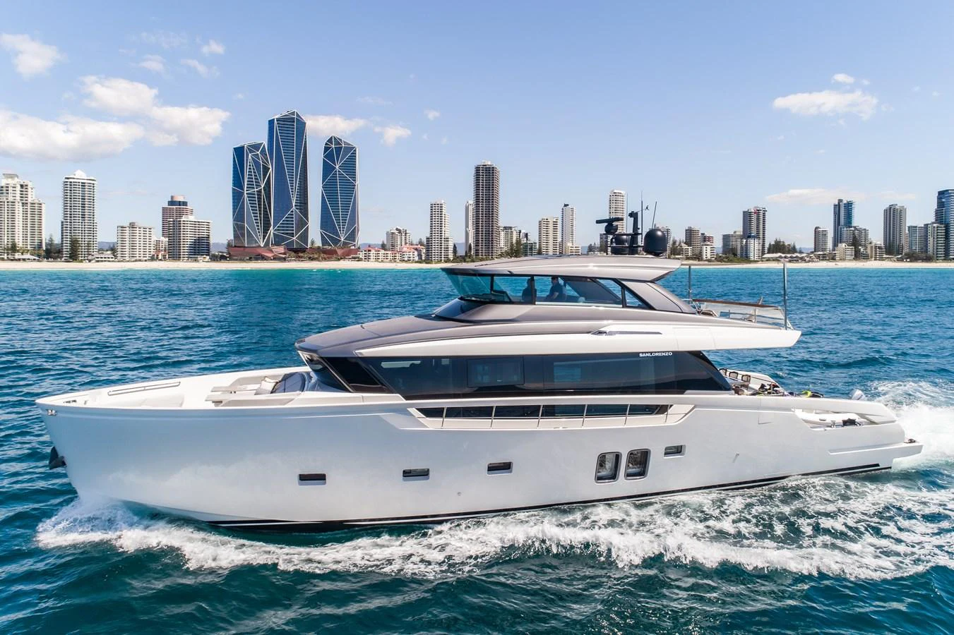 A sleek and modern yacht cruises along the water with a city skyline in the background. aboard VIOLETTA Yacht for Sale