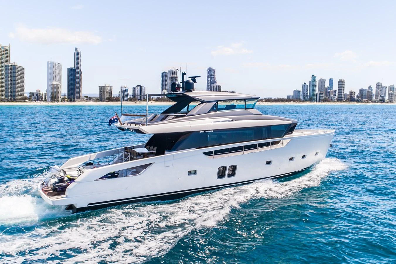 A sleek, modern yacht cruising on the water with a city skyline in the background. aboard VIOLETTA Yacht for Sale
