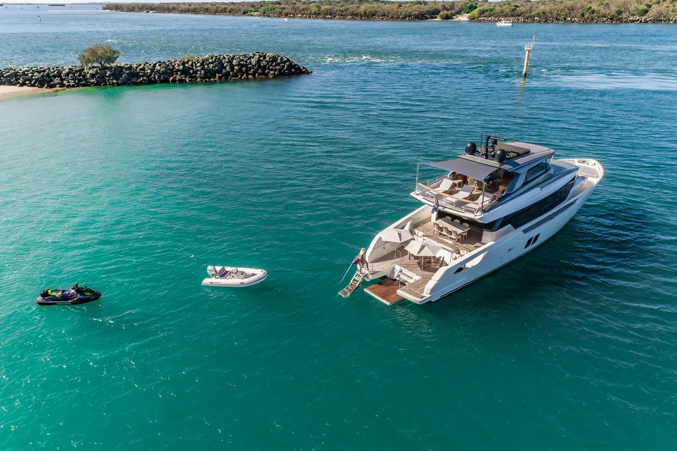 A luxurious yacht is anchored in a serene coastal area, with a tender and a jet ski nearby. aboard VIOLETTA Yacht for Sale