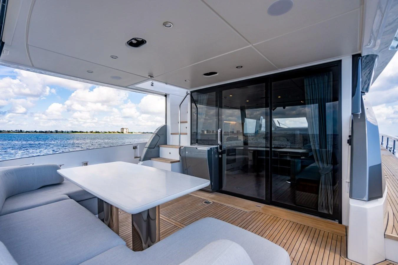 The aft deck offers a spacious and comfortable outdoor seating area with a dining table, perfect for enjoying meals with a view of the water. aboard EFFORTLESS Yacht for Sale